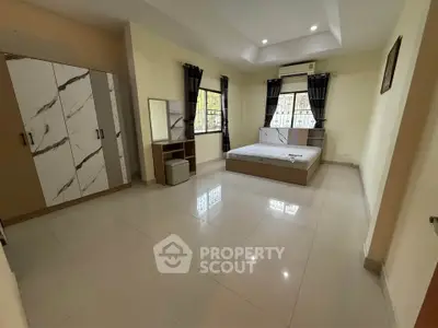 Spacious bedroom with modern furniture and large windows for natural light.