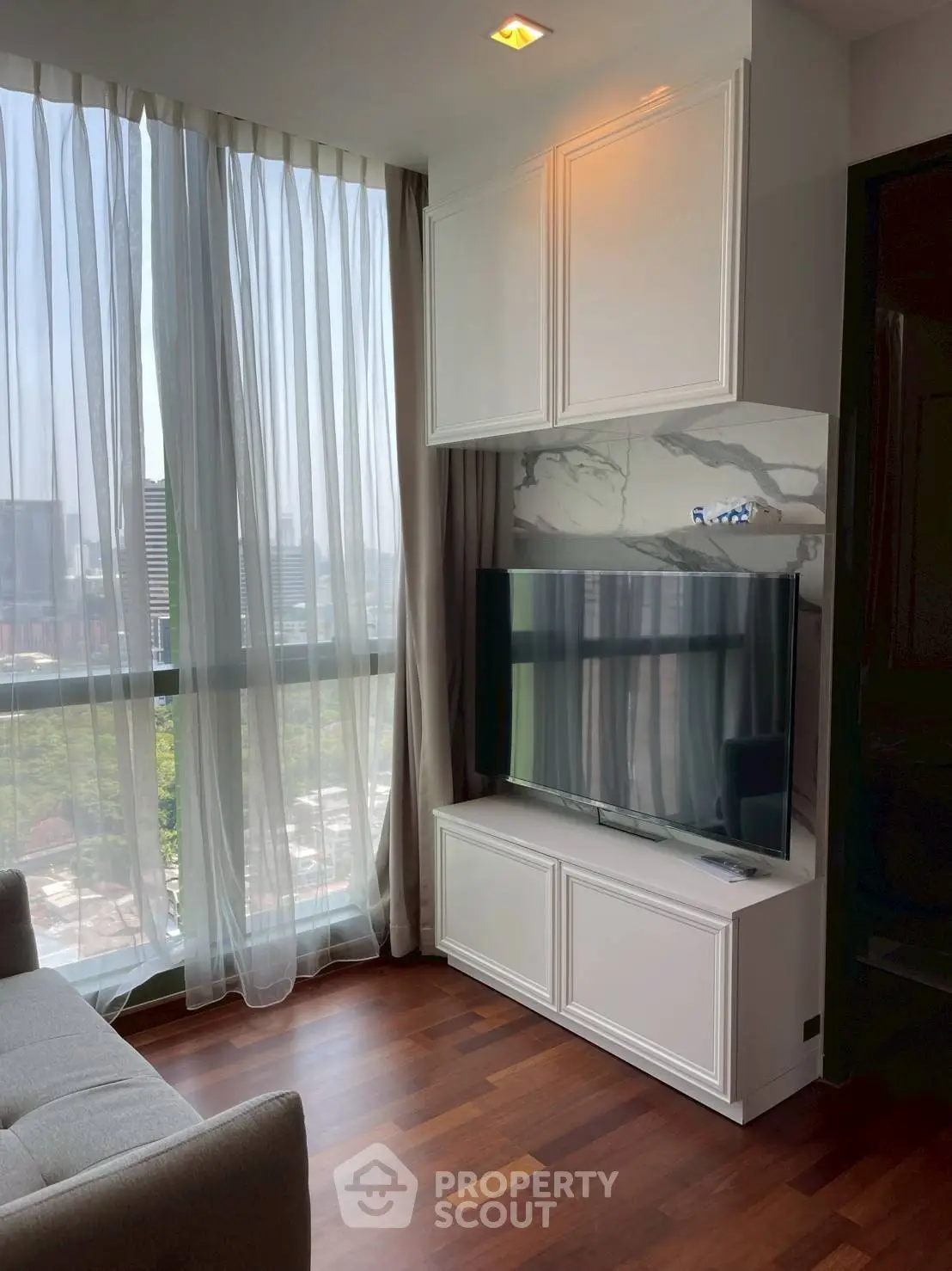 Modern living room with large window and sleek TV setup, offering a bright and inviting atmosphere.