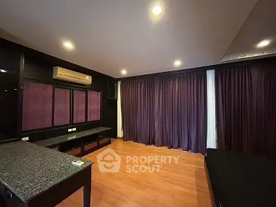 Spacious bedroom with wooden flooring and elegant dark curtains, featuring modern lighting and air conditioning.