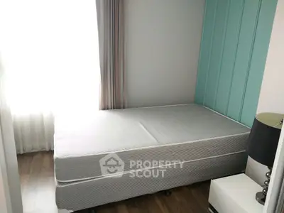 Cozy bedroom with natural light and modern decor, featuring a single bed and stylish lamp.