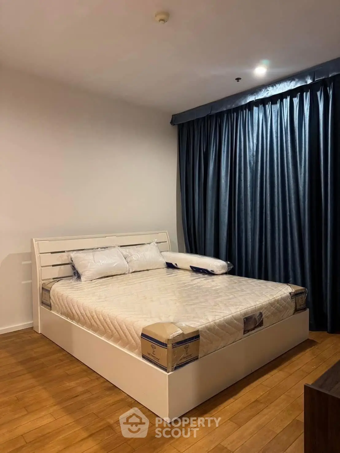 Spacious bedroom with elegant wooden flooring and cozy bed setup