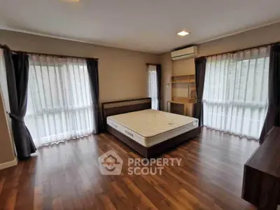 Spacious bedroom with large windows and wooden flooring