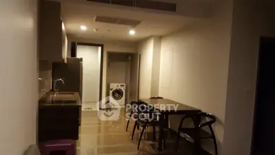 Modern apartment interior with kitchen and dining area featuring sleek furniture and appliances.