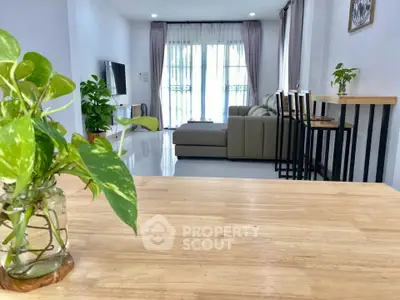 Modern living room with stylish decor and natural light, featuring a cozy sofa and indoor plants.