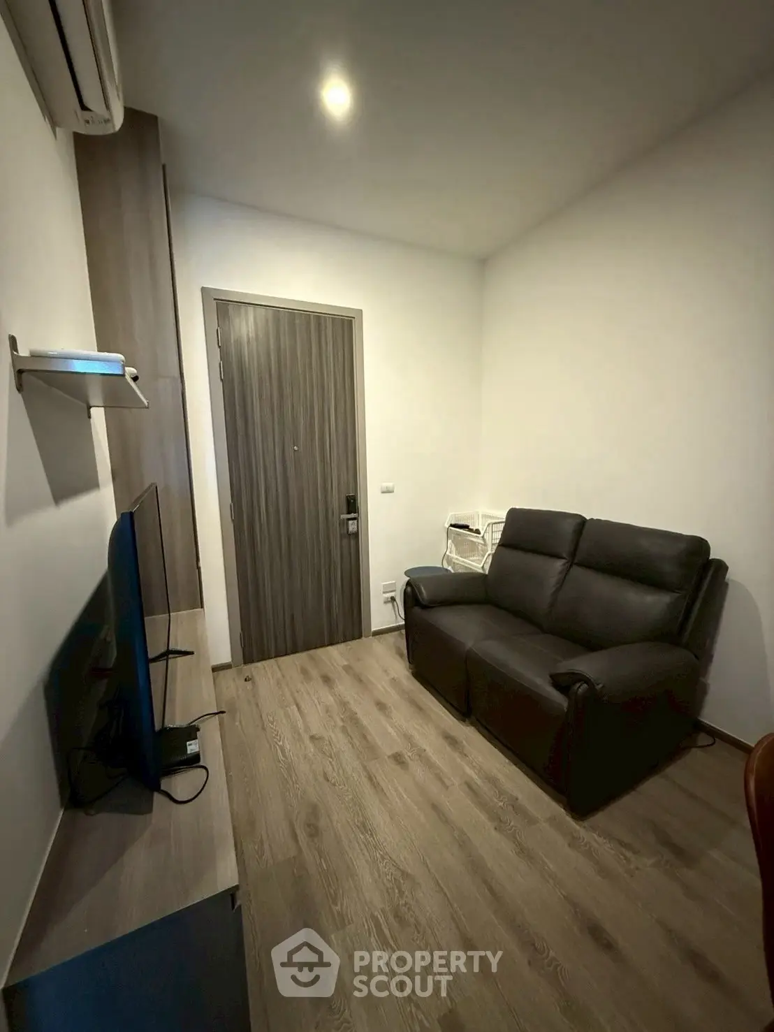 Cozy living room with modern sofa and flat-screen TV, perfect for relaxation.
