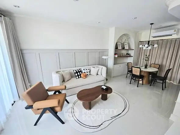 Modern living room with stylish furniture and dining area, featuring neutral tones and elegant decor.