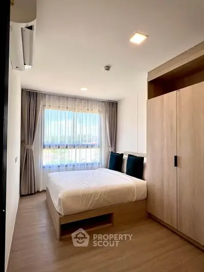 Modern bedroom with large window and stylish wooden wardrobe