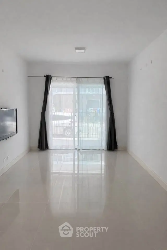 Spacious empty living room with large windows and modern tile flooring.