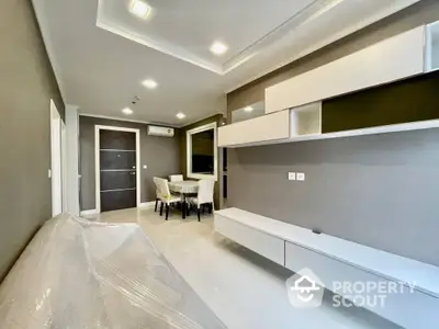 Elegant modern living room with glossy white cabinetry, recessed lighting, and a spacious dining area, perfect for entertaining guests in style.