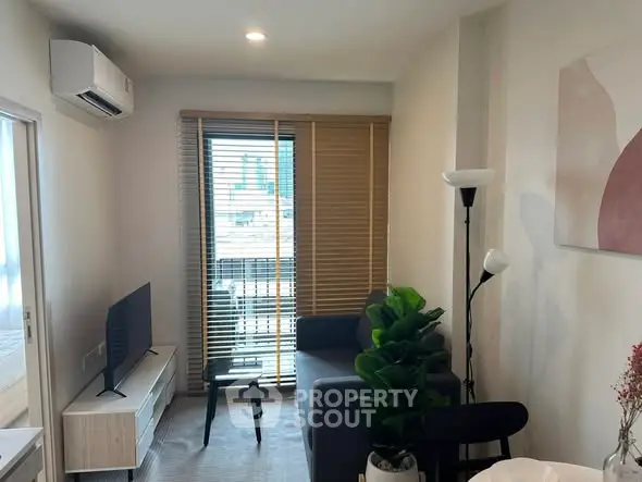 Modern living room with sleek furniture and natural light from large window.