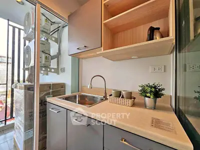 Modern kitchen with sleek cabinetry and balcony view, featuring a compact design and stylish decor.