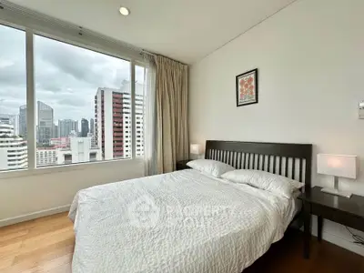 Modern bedroom with city view, featuring a cozy bed and large window in a high-rise apartment.