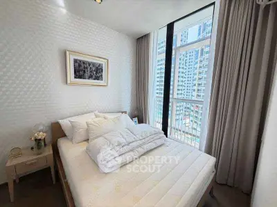 Modern bedroom with large windows offering city views, featuring a cozy bed and elegant decor.