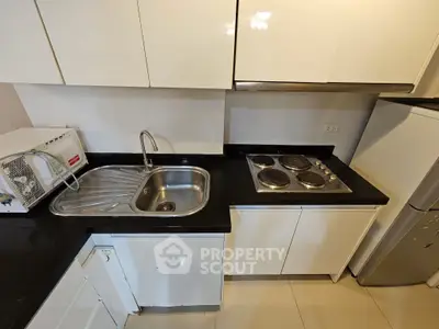 Modern kitchen with sleek cabinets, stainless steel sink, and electric stove