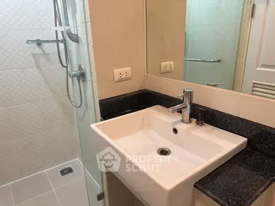 Modern bathroom with sleek sink and shower area in contemporary apartment.