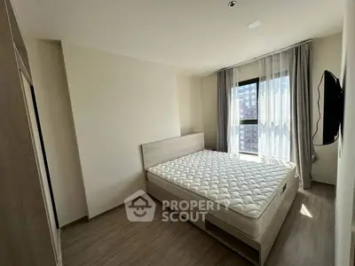 Modern bedroom with natural light and minimalist design, featuring a comfortable bed and wall-mounted TV.