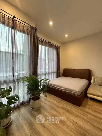 Modern bedroom with large windows and stylish decor in a cozy apartment.