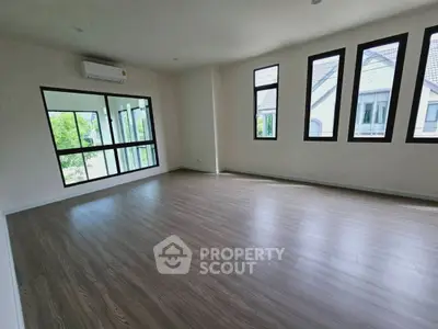 Spacious empty room with large windows and wooden flooring, perfect for customization.