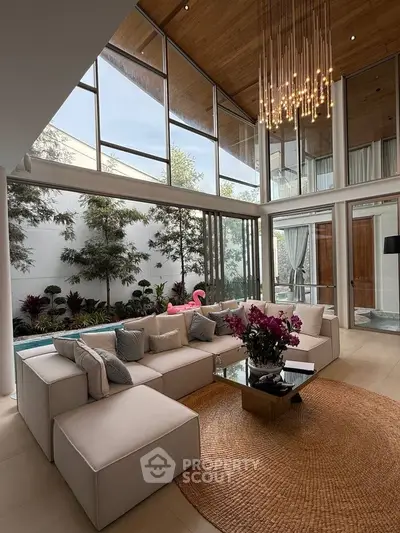 Luxurious living room with high ceilings, elegant chandelier, and poolside view.
