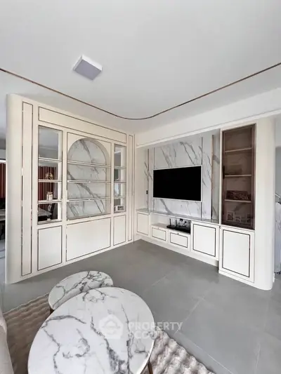 Elegant living room with marble tables and built-in TV unit, showcasing modern interior design.