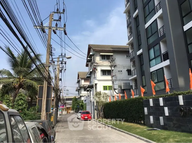Modern apartment building exterior with street view and parked cars.