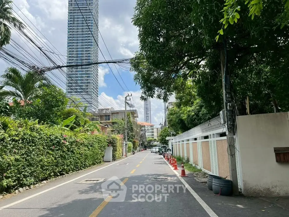 Scenic urban street view with lush greenery and modern high-rise buildings in the background.