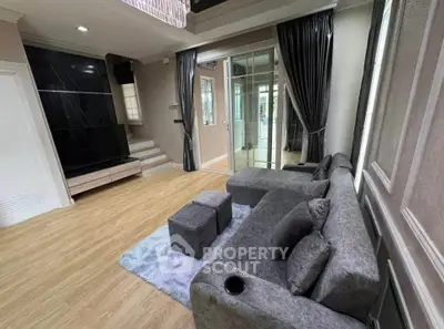 Modern living room with stylish gray sofa, elegant curtains, and sleek wooden flooring.