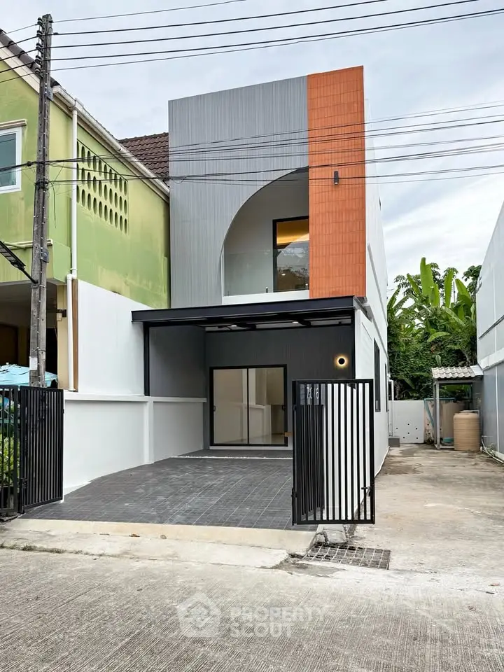 Modern two-story house with unique facade and gated driveway in urban setting.