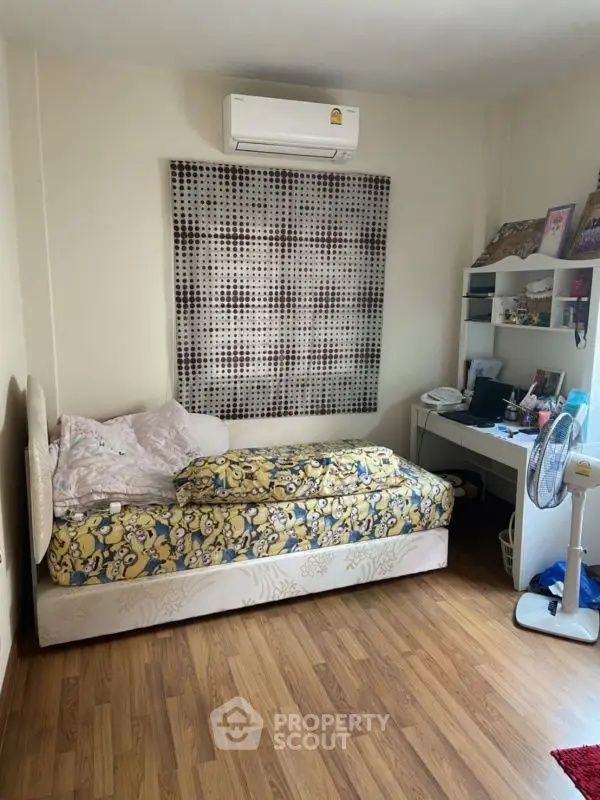 Cozy bedroom with air conditioning and wooden flooring, featuring a single bed and study desk.
