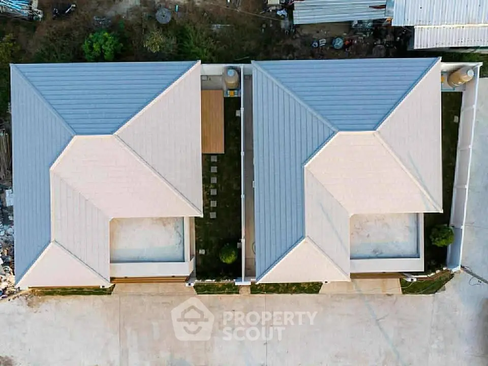 Aerial view of modern twin houses with sleek roofs and shared courtyard.