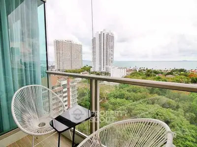 Stunning balcony view with modern chairs overlooking cityscape and ocean.