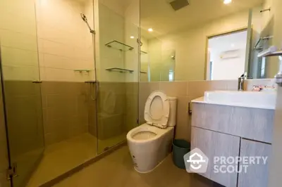 Modern bathroom with glass shower and sleek vanity in contemporary home.