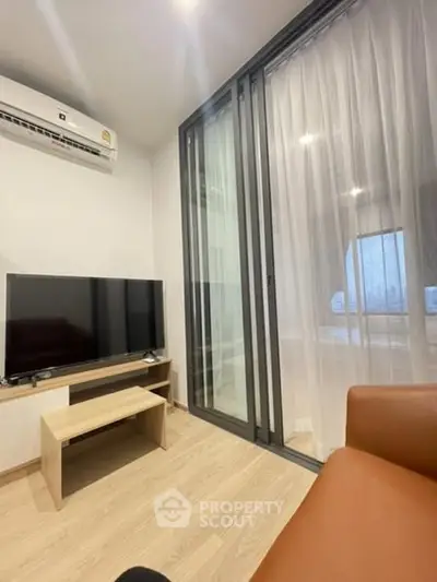 Modern living room with TV, air conditioning, and sliding glass door.