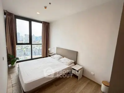 Modern bedroom with city view and natural light in high-rise apartment.