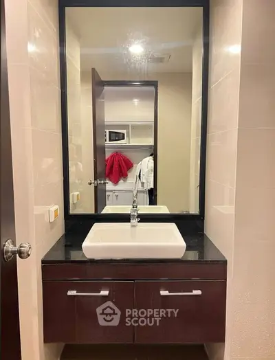 Modern bathroom with sleek vanity and large mirror, featuring contemporary design and ample storage space.
