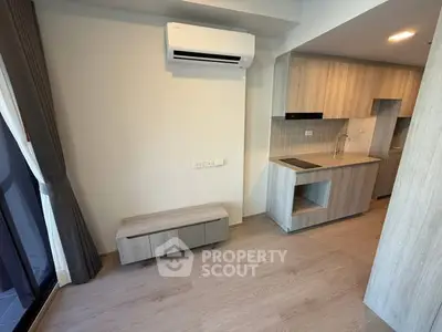 Modern apartment interior with sleek kitchen and air conditioning, featuring light wood flooring and cabinetry.
