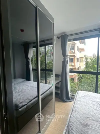 Modern bedroom with large mirrored wardrobe and city view window