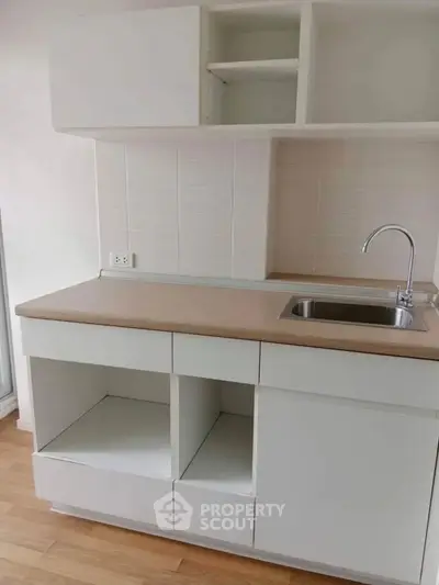 Modern minimalist kitchen with sleek cabinetry and stainless steel sink, perfect for compact living spaces.