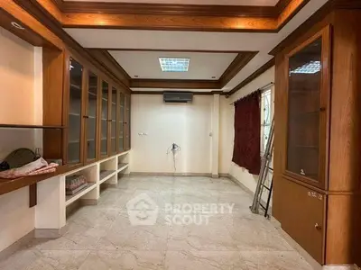 Spacious room with built-in wooden cabinets and marble flooring, ideal for a home office or study.