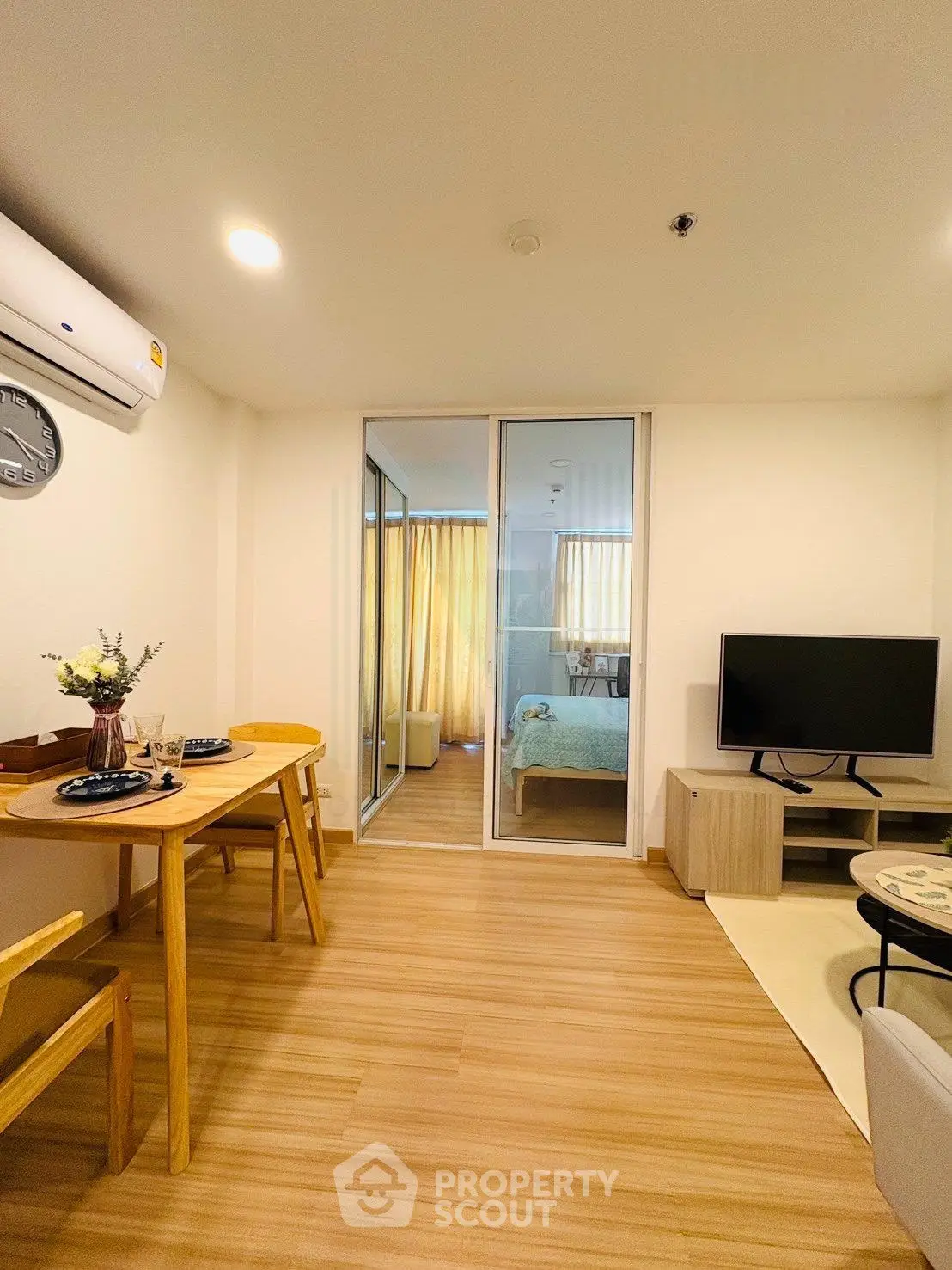 Modern living room with dining area and view into cozy bedroom