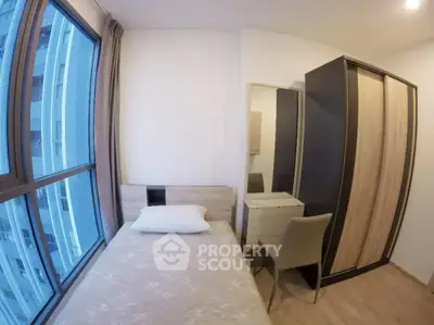 Cozy bedroom with modern furniture and large window offering city views.