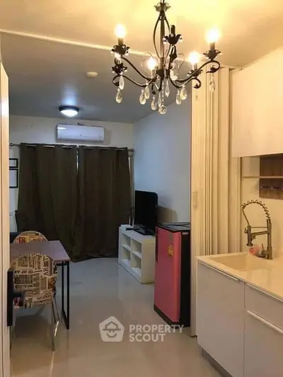 Cozy living room with chandelier and compact kitchen in modern apartment