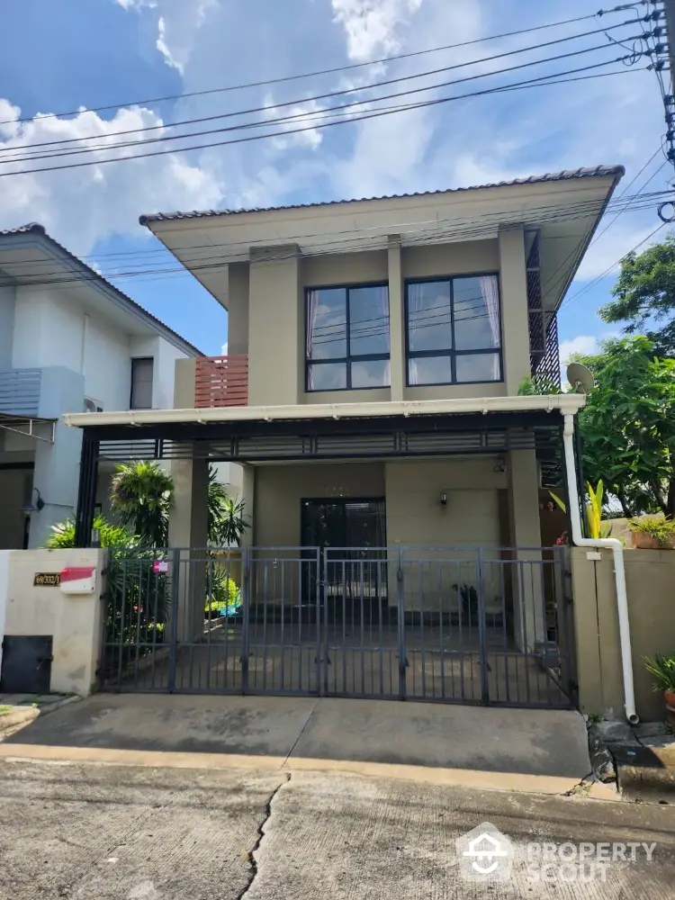 Charming two-story house with modern facade and gated entrance in a serene neighborhood.