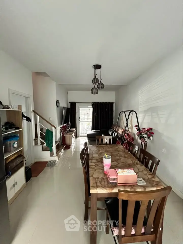 Spacious dining area with elegant wooden table and chairs, modern lighting, and cozy living space.