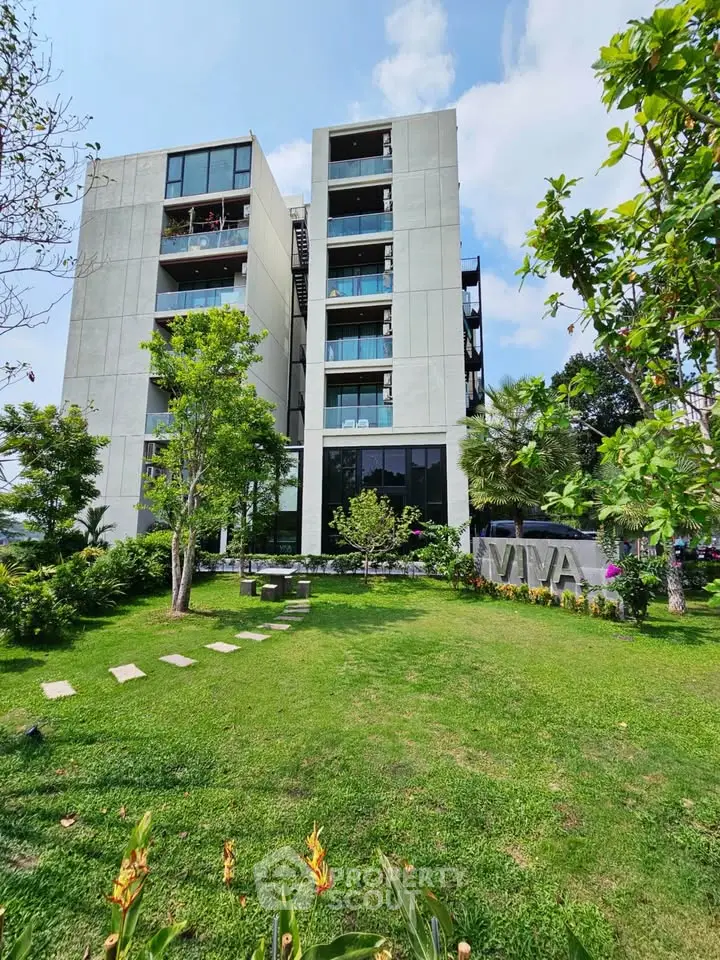 Modern apartment building with lush green garden and clear blue sky.