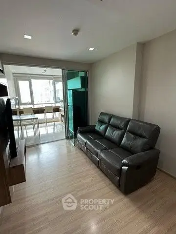 Modern living room with sleek leather sofa and open layout leading to dining area.
