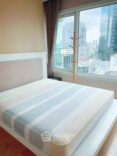 Modern bedroom with city view and large windows in high-rise apartment