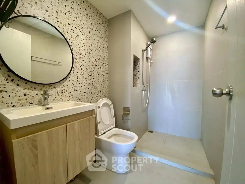 Modern bathroom with terrazzo wall, round mirror, and walk-in shower