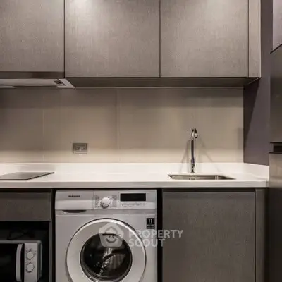 Modern kitchen with integrated washing machine and sleek cabinetry.