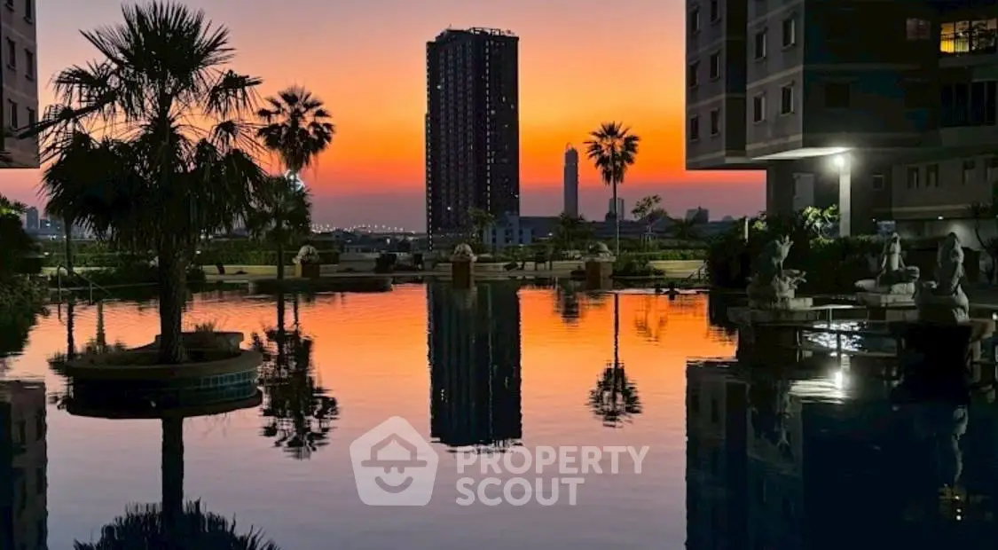 Stunning sunset view from luxury apartment complex with serene pool and palm trees.